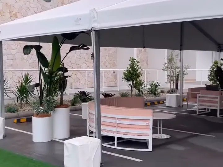 Strelitzia, palms and potted trees in white pots styled around white and pink lounges under a marquee