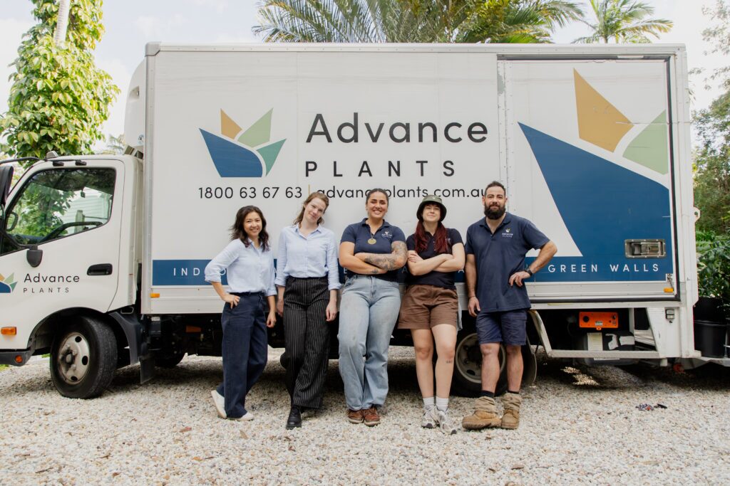 Five Advance Plants team members standing together in front of the company delivery truck
