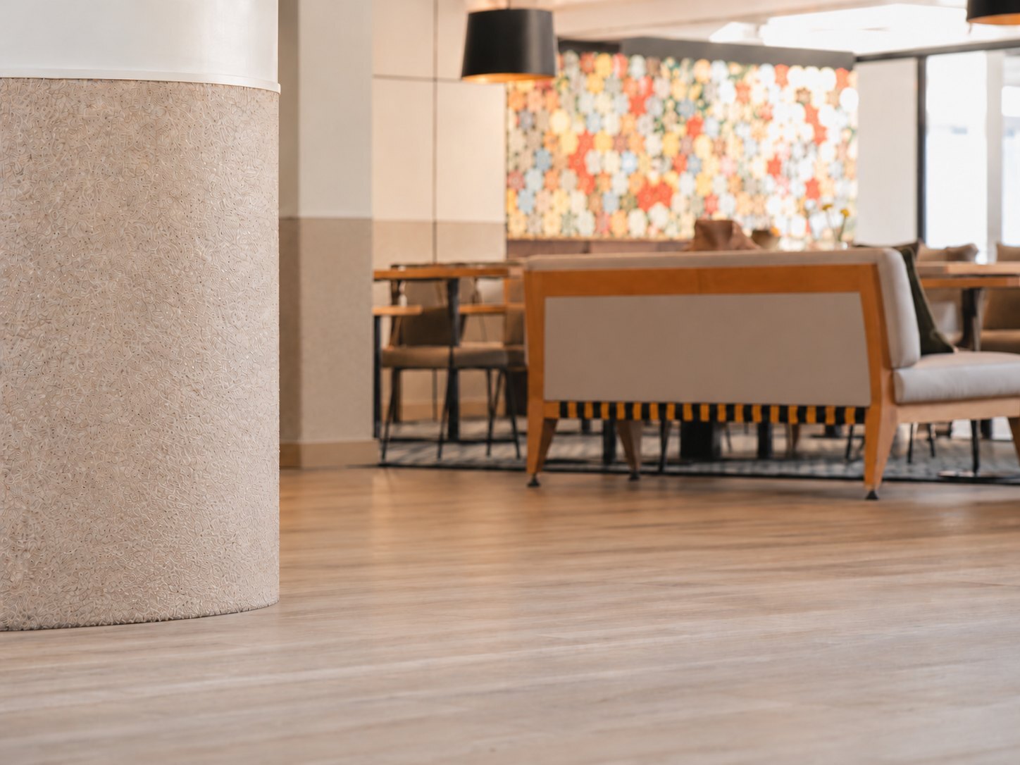 An empty Gold Coast hotel lobby lounge with bare timber floor beside a rendered column, before designer pots and planting were installed